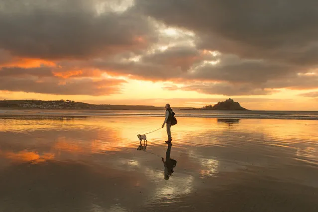 A dog walker on the beach at St Michael’s Mount in Marazion, England at sunrise January 10, 2020. (Photo by Simon Maycock/Alamy Live News)