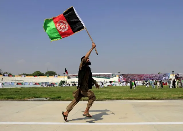 An Afghan man holds an Afghanistan national flag during a ceremony marking the country's 96th Independence Day in Jalalabad province, Afghanistan August 19, 2015. (Photo by Reuters/Parwiz)