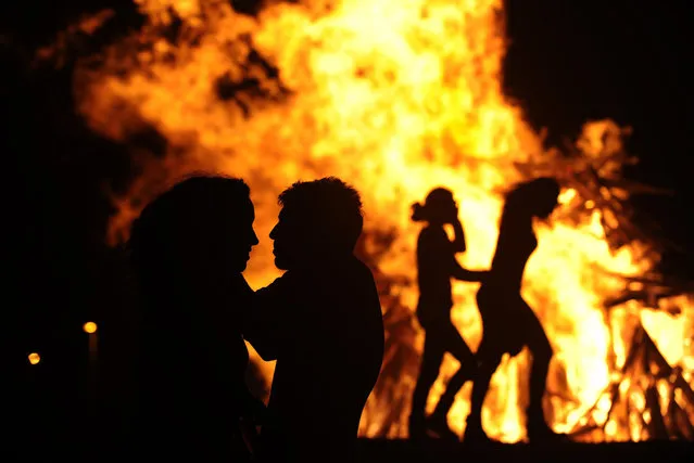 People attend a party held during the night of the San Juan bonfire on the beach of Playa de Poniente in Gijon early June 24, 2014. Fires formed by burning unwanted furniture, old school books, wood and effigies of malign spirits are seen across Spain as people celebrate the night of San Juan, a purification ceremony coinciding with the summer solstice. (Photo by Eloy Alonso/Reuters)