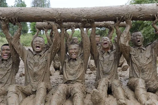 Paramilitary soldiers lift logs during a physical training in mud in Chuzhou, Anhui province, July 18, 2012. Picture taken July 18, 2012. (Photo by China Daily/Reuters)