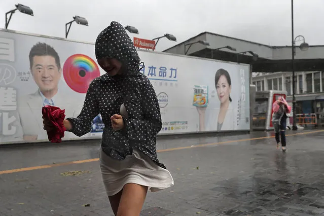 A woman walk against the strong wind caused by tropical storm Pakhar on the waterfront of Victoria Habour in Hong Kong, Sunday, August 27, 2017. The Hong Kong Observatory says Severe Tropical Storm Pakhar has made landfall over Taishan of Guangdong. (Photo by Vincent Yu/AP Photo)