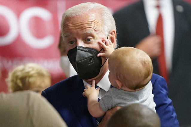 President Joe Biden holds a baby as he visits a COVID-19 vaccination clinic at the Church of the Holy Communion Tuesday, June 21, 2022, in Washington. (Photo by Evan Vucci/AP Photo)