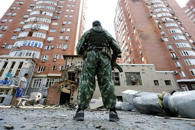 An armed pro-Russian separatist stands in front of damaged buildings following what locals say was shelling by Ukrainian forces in Donetsk August 7, 2014. The Ukrainian government said on Thursday it was suspending a ceasefire with separatist rebels at the crash site of the Malaysian airliner after an international recovery mission had been halted. (Photo by Sergei Karpukhin/Reuters)