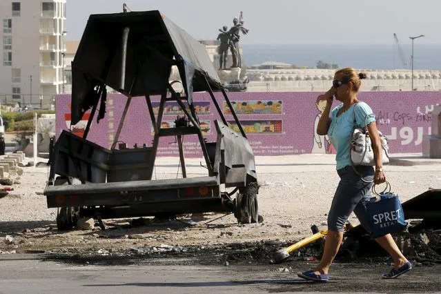 A woman covers her nose as she walks past a burnt police vehicle and charred remains of objects set on fire on Sunday by protesters near Martyrs' Square in downtown Beirut, Lebanon August 24, 2015. Lebanese protesters said they had postponed a demonstration set for Monday evening, after rallies a day earlier triggered clashes with security forces in Beirut. (Photo by Jamal Saidi/Reuters)