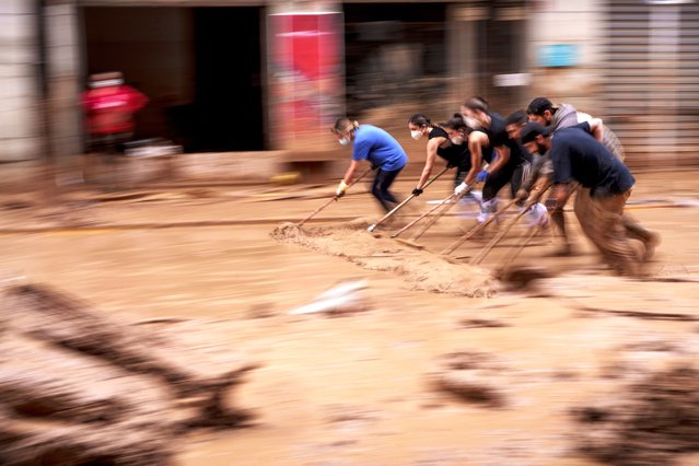 People clear mud from a street in an area affected by floods in Catarroja, Spain, on Monday, November 4, 2024. (Photo by Manu Fernandez/AP Photo)