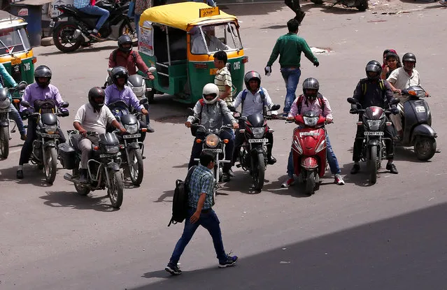 People riding motorcycles wait to cross a road at a traffic signal in New Delhi, India, June 16, 2016. (Photo by Adnan Abidi/Reuters)