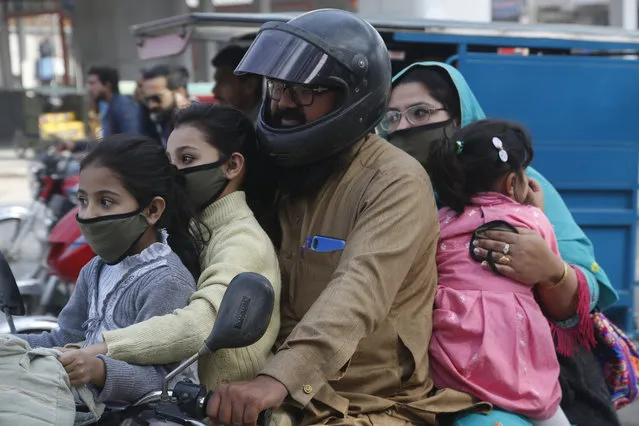A Pakistani family wears face masks to help prevent exposure to the new coronavirus as they travel on a motorbike in Lahore, Pakistan, Monday, March 16, 2020. For most people, the new coronavirus causes only mild or moderate symptoms. For some it can cause more severe illness. (Photo by K.M. Chaudhry/AP Photo)