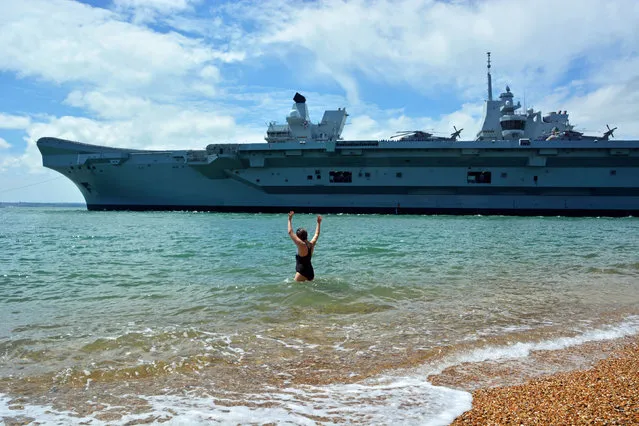 Swimmer Dale Marie waves off the Royal Navy’s aircraft carrier HMS Queen Elizabeth as it sailed through the mouth of Portsmouth Harbour in England, to set sail for sea trials on June 17, 2019. (Photo by Ben Mitchell/PA Wire Press Association)