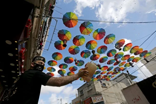 A Palestinian worker sprays water outside shops decorated ahead of the holy fasting month, amid concerns about the spread of the coronavirus disease (COVID-19), in the southern Gaza Strip on April 22, 2020. (Photo by Ibraheem Abu Mustafa/Reuters)