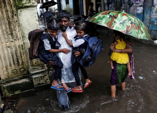 A man carries schoolchildren through a flooded street during monsoon rains in Mumbai, India, August 1, 2016. (Photo by Danish Siddiqui/Reuters)