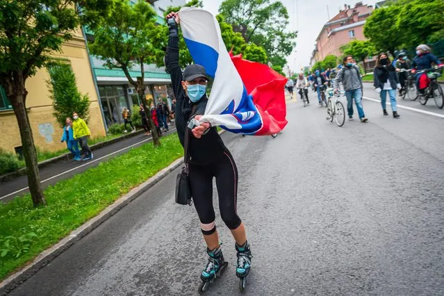 A Slovenian citizen, wearing a protective mask, waves a Slovenian flag, on May 15, 2020, as she takes part in a demonstration to block the centre of the capital Ljubljana, to protest against the centre-right government, accusing it of corruption and of using the COVID-19 (the novel coronavirus) crisis to restrict freedom. (Photo by Jure Makovec/AFP Photo)
