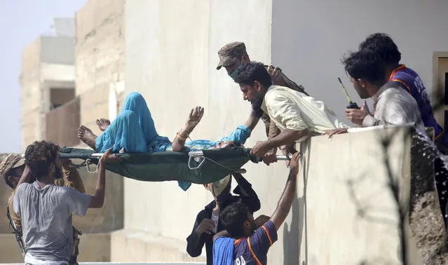 Volunteers carry an injured person at the site of a plane crash in Karachi, Pakistan, Friday, May 22, 2020. An aviation official says a passenger plane belonging to state-run Pakistan International Airlines carrying more than 100 passengers and crew has crashed near the southern port city of Karachi. (Photo by Fareed Khan/AP Photo)