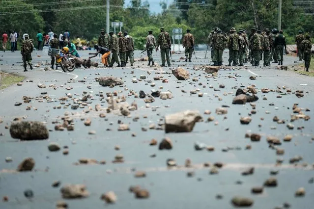 Kenyan police officers remove stones and rocks set up as barricade by National Super Alliance (NASA) supporters in Ahero, about 25 km east from Kisumu, Kenya, on October 26, 2017, during Kenya' s re- election voting. (Photo by Yasuyoshi Chiba/AFP Photo)