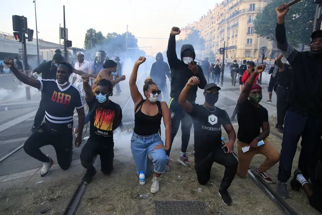 Protesters react during a demonstration Tuesday, June 2, 2020 in Paris. Paris riot officers fired tear gas as scattered protesters threw projectiles and set fires at an unauthorized demonstration against police violence and racial injustice. Several thousand people rallied peacefully for two hours around the main Paris courthouse in homage to George Floyd and to Adama Traore, a French black man who died in police custody. (Photo by Michel Euler/AP Photo)