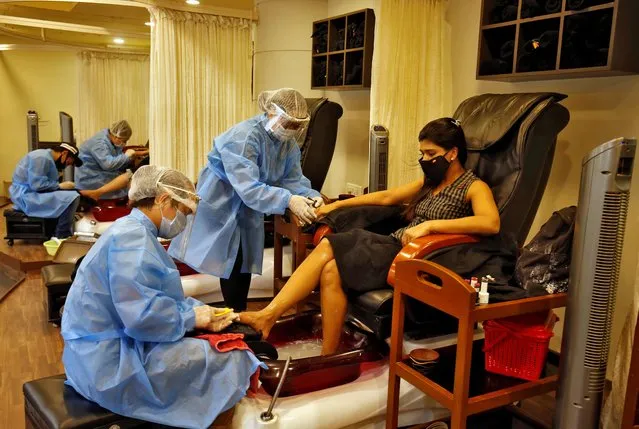 Beauticians wearing protective gear tend to their customers inside a parlor at a shopping mall after authorities allowed the reopening of malls in Ahmedabad, India, June 8, 2020. (Photo by Amit Dave/Reuters)