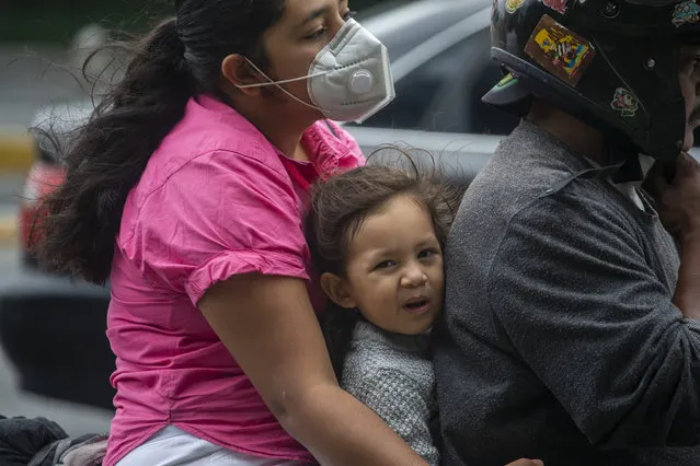 A family rides a motorcycle past a checkpoint during the first day of a system limiting the days that vehicles can go out as a way to curb the spread of COVID-19, ordered by the government for the metropolitan area of Guatemala City, Tuesday, June 16, 2020. (Photo by Moises Castillo/AP Photo)