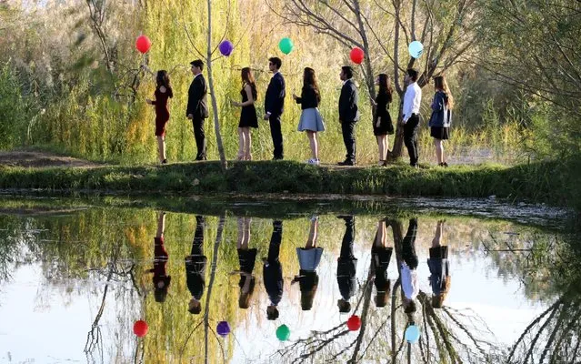 People, holding balloons, pose near a pond on an autumn day in Sultanhisar district of Aydin, Turkey on November 19, 2017. Sema (not seen) and Arif Elibol (not seen) couple, who have been married for 44 years, had bought a swamp-land and with their almost 20-year-long efforts, they have been transformed it into a natural wonder. The pond and the surrounding environment, used by photographers as a natural backdrop, are the one of the preferred locations for wedding couples, especially on weekends. (Photo by Mehmet Calik/Anadolu Agency/Getty Images)
