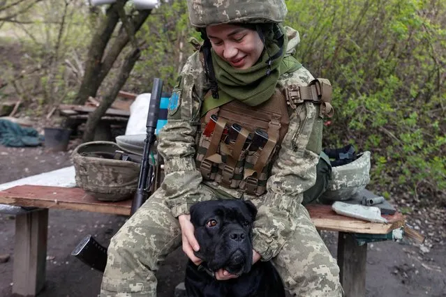 A Ukrainian service member pets a dog at a position, as Russia?s attack on Ukraine continues, in Donetsk Region, Ukraine on April 22, 2022. (Photo by Serhii Nuzhnenko/Reuters)