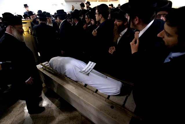 Ultra Orthodox Jewish men gather around the body of Mirah Sharf, who was killed in the southern town of Kiryat Malachi by a rocket fired by Palestinian militants from the Gaza Strip, during her funeral in Jerusalem. Gaza militants led by the ruling Hamas Islamic group showered Israel with more than 150 rockets in an unprecedented assault Thursday, killing three Israelis and trying for the first time to strike Tel Aviv, the densely populated heart of the Jewish state. (Photo by Sebastian Scheiner/Associated Press)