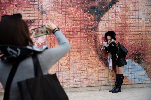 Plaça Nova, November 2024. Josephine, a tourist from the US, has her picture taken in front of the mural called “The World Begins With Every Kiss”. (Photo by Stefan Nieland/The Guardian)