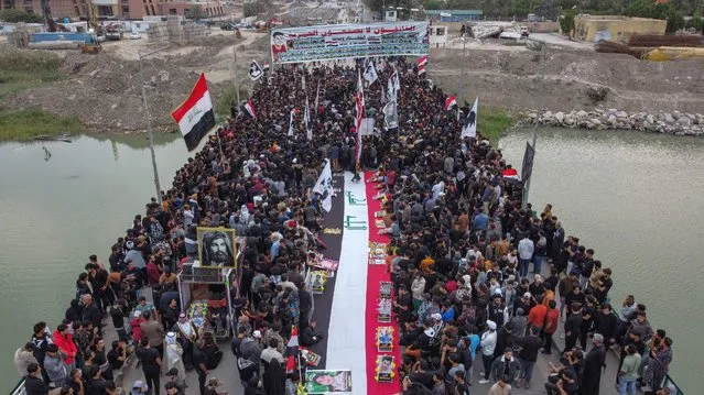 This aerial view shows locals in the city of Nasiriyah in Iraq's southern Dhi Qar province gathering along al-Zaitoon (Olive) bridge on November 28, 2022 to commemorate the third anniversary of the quelling of a protest and sit-in against deteriorating living conditions and lack of services at the same location by Iraqi security forces. (Photo by Asaad Niazi/AFP Photo)
