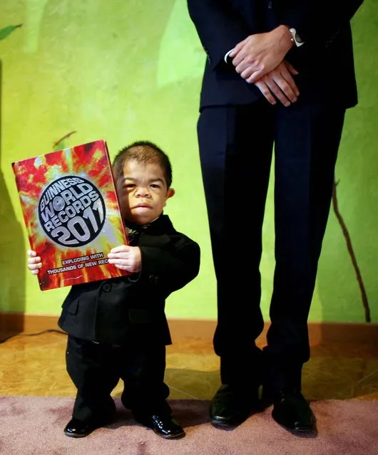 Edward Nino Hernandez, 24, poses for a portrait as he holds the Guinness World Record Book 2011 in Bogota, Colombia, on September 2, 2010. Nino is recognized as the world's shortest man in the new Guinness World Records 2011. (Photo by William Fernando Martinez/Associated Press)