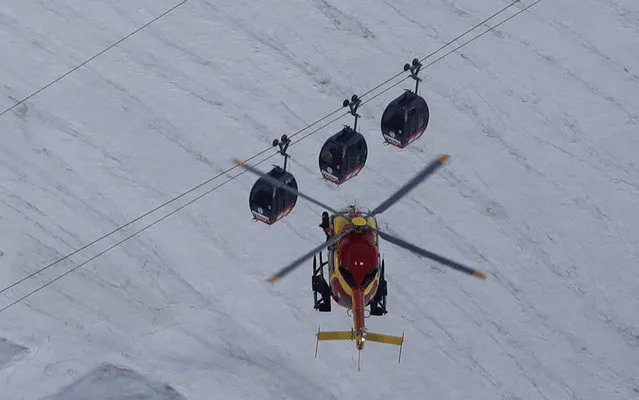 An EC-135 helicopter operated by the French Societe' Civile hovers, Friday, September 9, 2016, near three cars of the Panoramic Mont Blanc cable car that stalled around 4 p.m. (14:00 GMT) on Thursday, after its cables reportedly tangled. The cable car carrying tourists stopped working at high altitude over the Mont Blanc massif in the Alps on Thursday, prompting a major rescue operation and leaving 45 people trapped in midair overnight, France's interior minister said. (Photo by Luca Bruno/AP Photo)