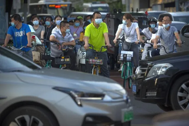People wearing face masks to protect against the coronavirus wait to cross an intersection in the central business district in Beijing, Friday, August 21, 2020. Authorities in China's capital announced on Thursday that masks would no longer be mandatory outdoors as a virus outbreak in the country's northwestern region of Xinjiang appears to have been brought under control. (Photo by Mark Schiefelbein/AP Photo)