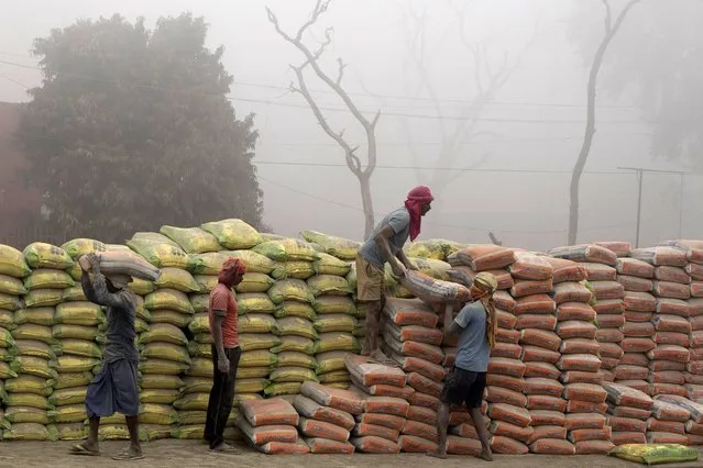 Laborers load cement sacks into a truck amidst morning fog near Buxar railway station in northern state of Bihar, India. Wednesday, December 21, 2022. (Photo by Rajesh Kumar Singh/AP Photo)