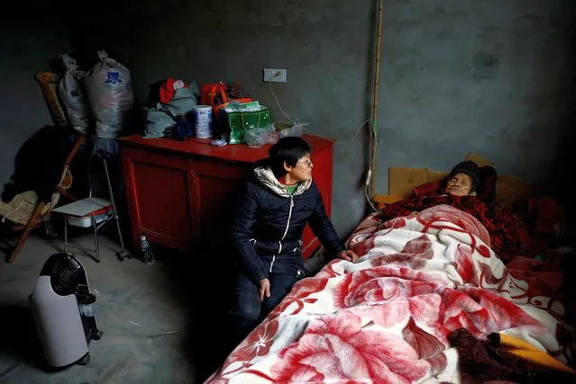 Liao Xiaofeng, 47, sits by an oxygen concentrator and her mother Chen Lifen, 86, upon returning from a clinic, at their home in a village of Lezhi county after strict measures to curb the coronavirus disease (COVID-19) were removed nationwide, in Ziyang, Sichuan province, China on December 29, 2022. (Photo by Tingshu Wang/Reuters)