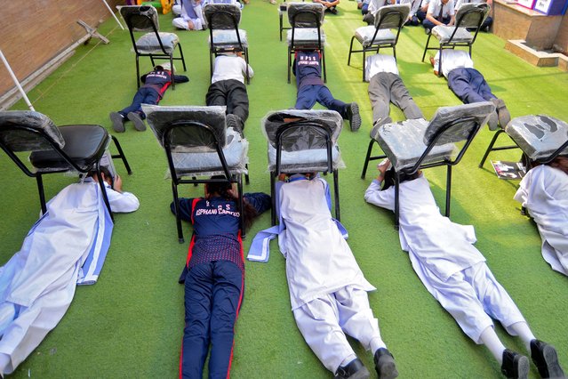 Students use chairs to cover their heads inside a classroom at a school during a mock drill for handling war situations, in Karachi, Pakistan, on May 9, 2025. (Photo by Imran Ali/Reuters)