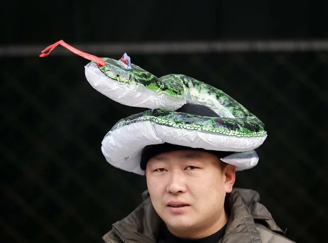A shop owner wears a snake-shaped ballon on his head in order to attract customers during the temple fair in Ditan Park, also known as the Temple of Earth, in Beijing February 9, 2013. The Lunar New Year, or Spring Festival, begins on February 10 and marks the start of the Year of the Snake, according to the Chinese zodiac. (Photo by Kim Kyung-Hoon/Reuters)