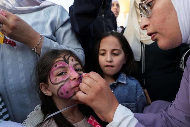 A Palestinian woman applies colours on a child's face on the first day of the Muslim holiday of Eid al-Adha on the Al-Aqsa compound, also known to Jews as the Temple Mount, in Jerusalem's Old City on June 6, 2025. (Photo by Ammar Awad/Reuters)