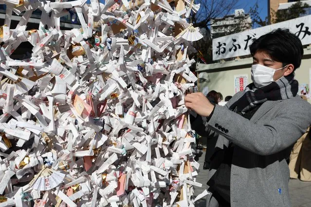 A man ties a “omikuji” fortune paper stripe at Kanda Myojin Shrine on January 04, 2023 in Tokyo, Japan. (Photo by Takashi Aoyama/Getty Images)