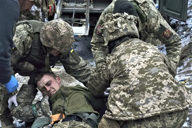 Military medics give first aid to a wounded soldier near Kremenna in the Luhansk region, Ukraine, Monday, January 16, 2023. (Photo by LIBKOS/AP Photo)