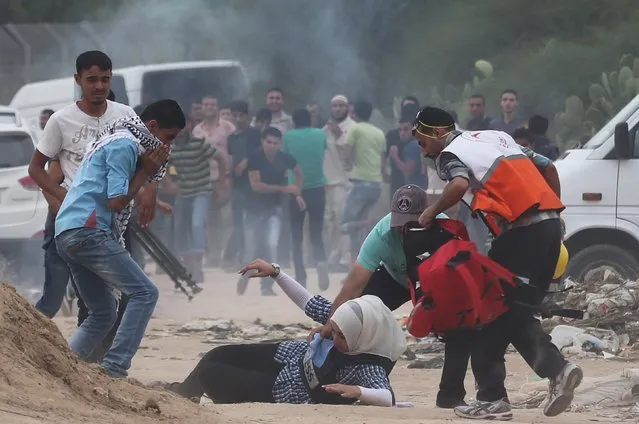 A female journalist lies on the ground after inhaling gas fired by Israeli troops during clashes with protesters near border between Israel and Central Gaza Strip October 23, 2015. Palestinian factions called for mass rallies against Israel in the occupied West Bank and East Jerusalem in a "day of rage" on Friday, as world and regional powers pressed on with talks to try to end more than three weeks of bloodshed. (Photo by Ibraheem Abu Mustafa/Reuters)