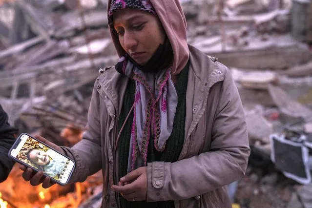 Aysegul Aytulun looks at a picture of a relative, Asel Aytulum, one of five family members who are thought to have died during the earthquake on Monday in Antakya, southeastern Turkey, on Sunday, February 12, 2023. The surviving relatives have been camped out in front of the damaged building, hoping that someone can recover the bodies. (Photo by Bernat Armangue/AP Photo)