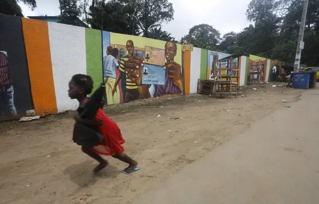 A girl runs near a mural that raises awareness about the electoral process in Adjame district, Abidjan October 19, 2015. (Photo by Thierre Gouegnon/Reuters)