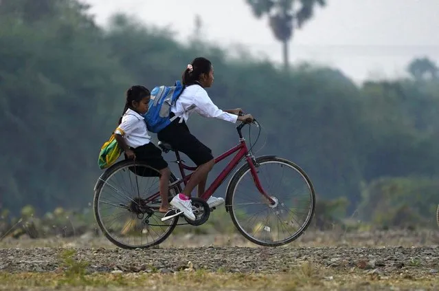 School children ride a bicycle to school on the outskirts of Phnom Penh, Cambodia, Wednesday, February 1, 2023. (Photo by Heng Sinith/AP Photo)