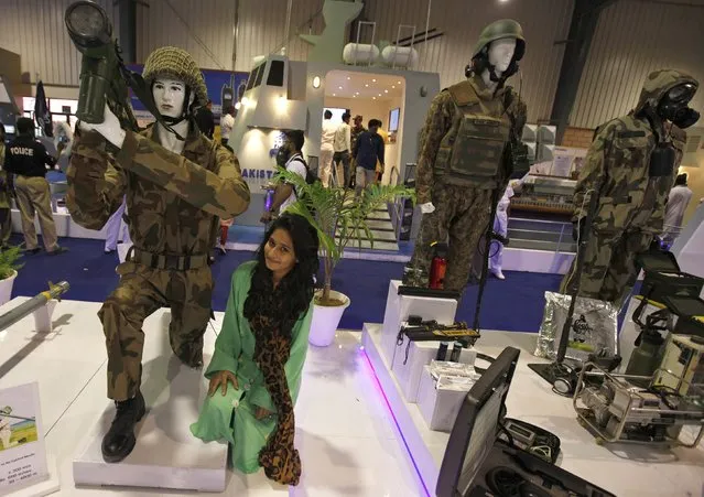 A visitor sits next to mannequins dressed in military fatigues as she is photographed by a family member (not pictured) during the last day of the International Defence Exhibition and Seminar “IDEAS 2014” in Karachi December 4, 2014. (Photo by Akhtar Soomro/Reuters)