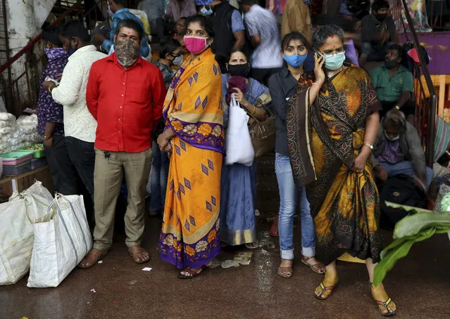 People wait to leave as it rains after shopping at a wholesale flower market ahead of the Hindu festival of Dussehra, in Bengaluru, India, Friday, October 23, 2020. Weeks after India fully opened up from a harsh lockdown and began to modestly turn a corner by cutting new infections by near half, a Hindu festival season is raising fears that the disease could spoil the hard-won gains. Health experts worry the festivals can set off a whole new cascade of infections, further testing and straining India’s battered health care system. (Photo by Aijaz Rahi/AP Photo)