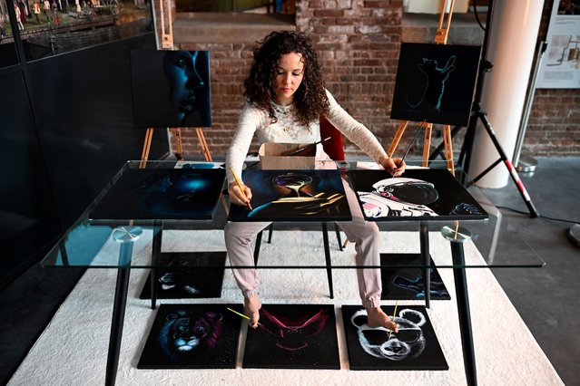 Dutch artist Rajacenna van Dam, paints ten paintings at once with both hands and feet, live in a museum in Vlaardingen, Netherlands on May 3, 2024. (Photo by John Thys/AFP Photo)