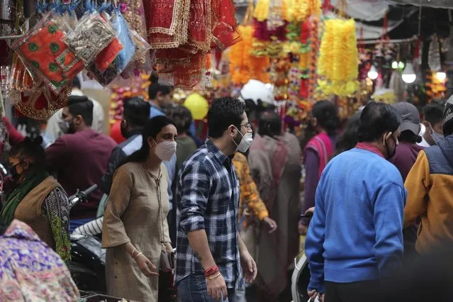 Indians wearing face masks as a precautionary measure against the coronavirus crowd a market during Diwali, the Hindu festival of lights, in Jammu, India, Saturday, November 14, 2020. (Photo by Channi Anand/AP Photo)