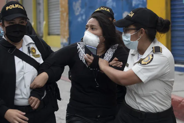 A woman is detained by police near the Congress building after protesters set a part of the building on fire, in Guatemala City, Saturday, November 21, 2020. Hundreds of protesters were protesting in various parts of the country Saturday against Guatemalan President Alejandro Giammattei and members of Congress for the approval of the 2021 budget that reduced funds for education, health and the fight for human rights. (Photo by Moises Castillo/AP Photo)