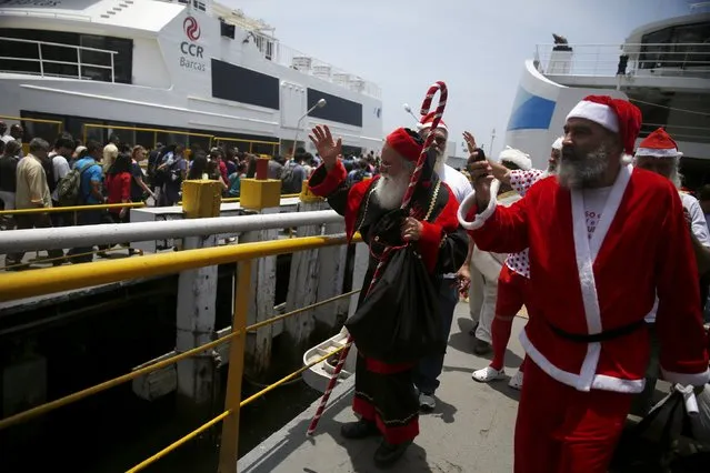 Students of the "Escola de Papai Noel do Brasil" (Brazil's school of Santa Claus) greet people as they arrive from the Guanabara bay after their graduation ceremony onboard a ferry, in Rio de Janeiro, Brazil, November 10, 2015. (Photo by Pilar Olivares/Reuters)