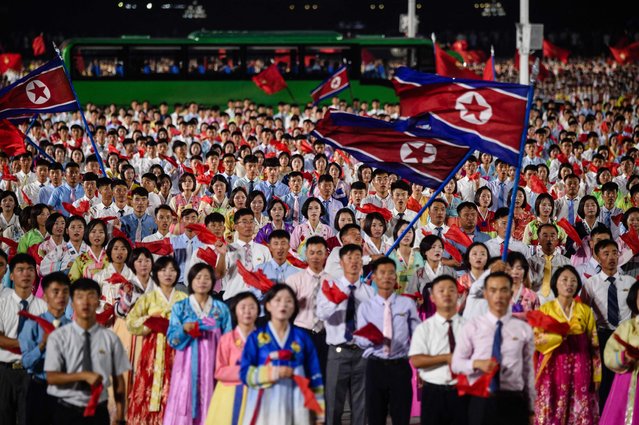 Participants hold national flags during an evening gala held as part of celebrations on the occasion of the 77th founding anniversary of North Korea at Kim Il Sung Square in Pyongyang on September 8, 2025. (Photo by Kim Won Jin/AFP Photo)