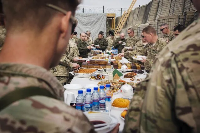 Brigadier General Christopher Bentley (2nd R) and U.S. soldiers from the 3rd Cavalry Regiment take part in a Christmas Eve celebration with soldiers from the Polish army's 21st Mountain Brigade on forward operating base Gamberi in the Laghman province of Afghanistan December 24, 2014. (Photo by Lucas Jackson/Reuters)