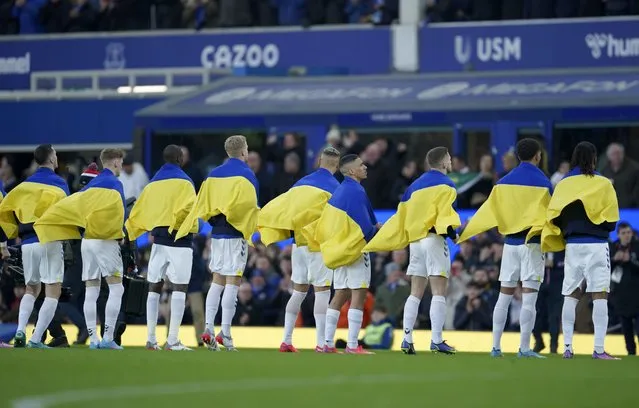 Everton players hold Ukrainian flags before the English Premier League soccer match between Everton and Manchester City at Goodison Park in Liverpool, England, Saturday, February 26, 2022. (Photo by Jon Super/AP Photo)
