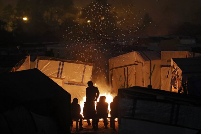 Sparks fly from a fire as migrants sit near for warmth at the end of the first day of the evacuation and transfer to reception centers of migrants living in the “Jungle” in Calais, France, October 24, 2016. (Photo by Philippe Wojazer/Reuters)