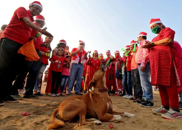 A dog howls as people wearing Santa hats take part in a laughter yoga session during Christmas celebrations on a beach in Mumbai, India, December 25, 2020. (Photo by Niharika Kulkarni/Reuters)